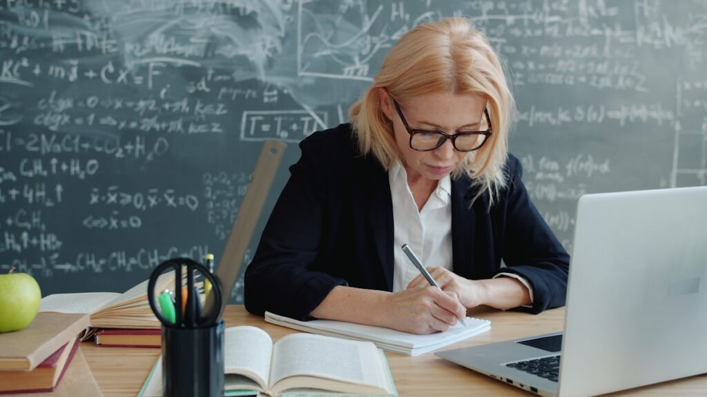 Profesora preparando clase con pizarra de fondo